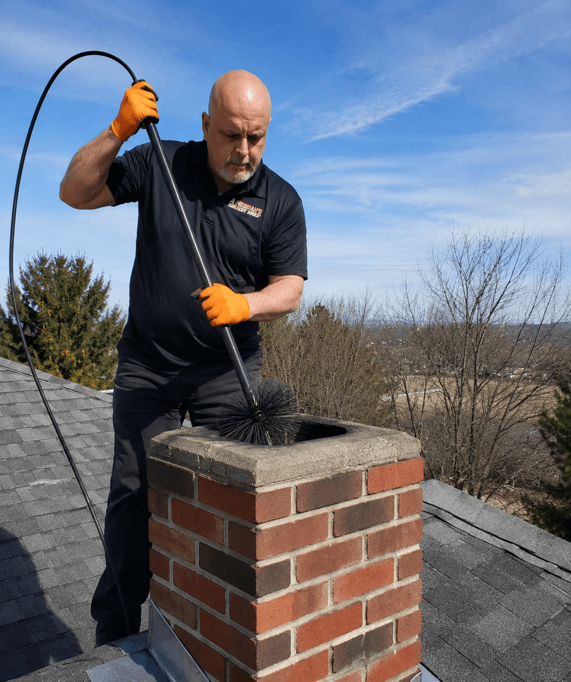 Bryan Fredrickson sweeping a chimney on a Treasure Valley rooftop