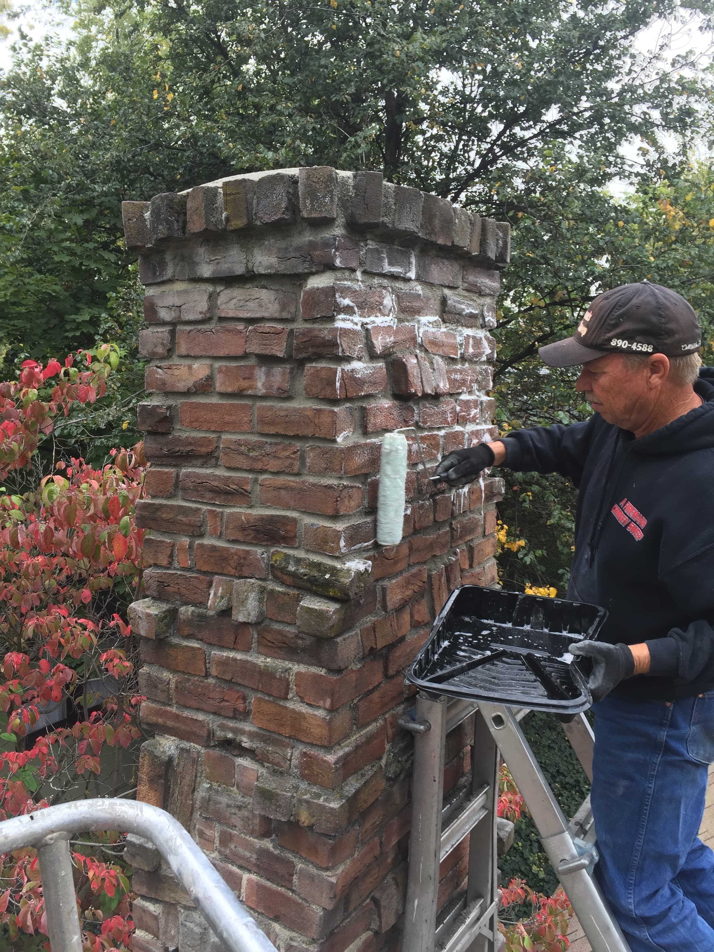 Applying waterproof sealant to brick chimney